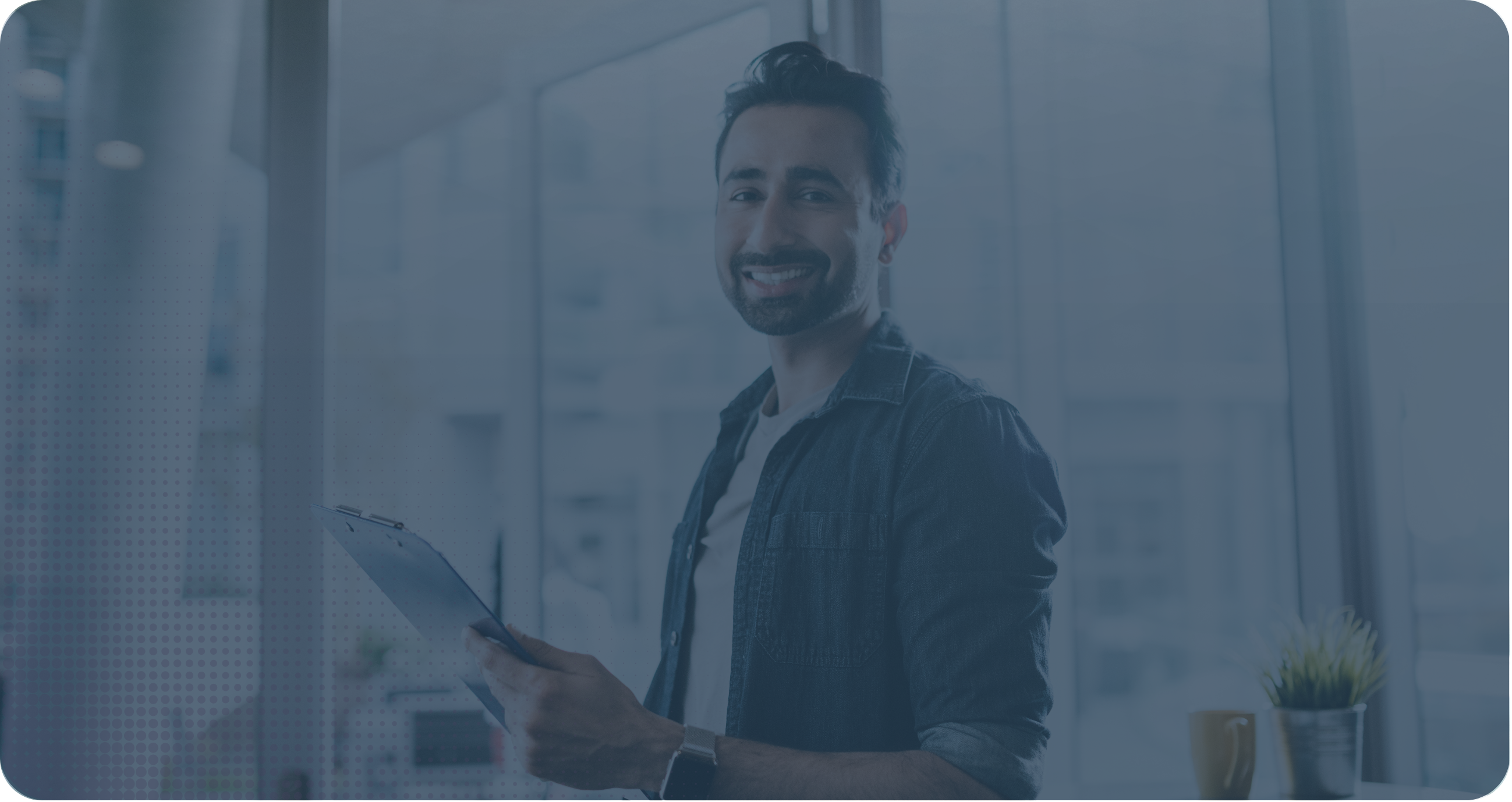 Smiling man holding a clipboard in an office.